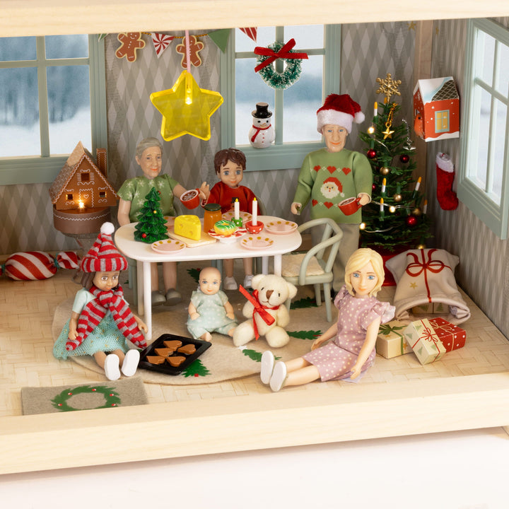Lundby dolls house family sitting together at the table for Christmas dinner beside a decorated Christmas tree, a festive seasonal play scene.