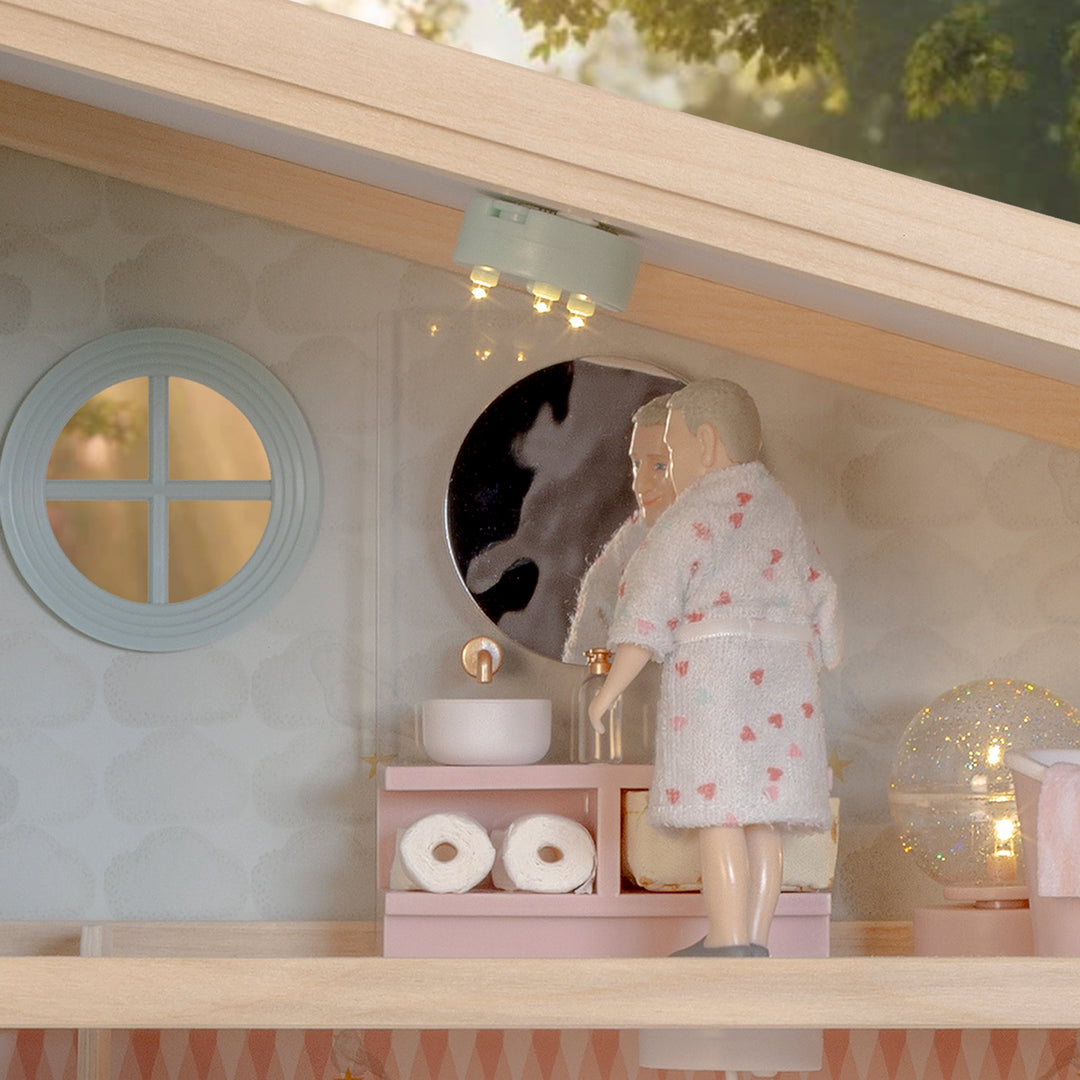 Lundby doll brushing his teeth as part of a cosy evening bedtime routine, in a bathroom lit by battery-powered LED dolls house lights.